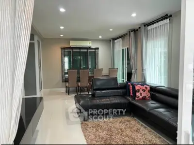 Spacious modern living room with sleek black leather sofa and elegant dining area, perfect for entertaining.