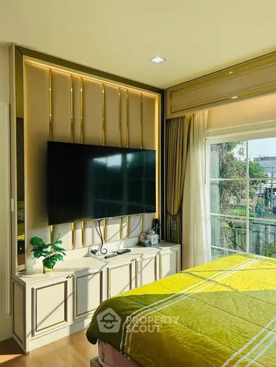 Luxurious bedroom with large TV and elegant decor, featuring a sunny window view.