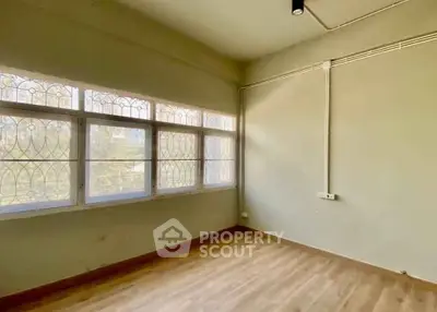 Spacious empty room with large windows and wooden flooring, ideal for customization.