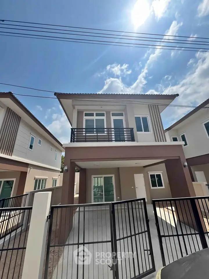 Modern two-story house with gated driveway and stylish facade under a clear blue sky.