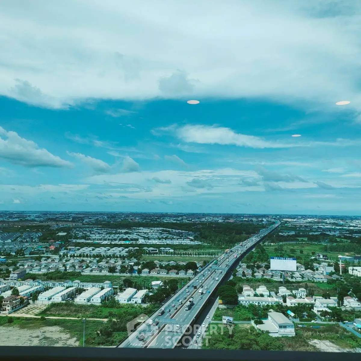 Stunning aerial view of urban landscape with highway and residential areas under a vibrant blue sky.