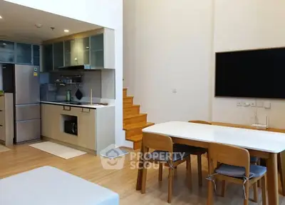 Modern open-layout kitchen and dining area with wooden flooring and staircase.