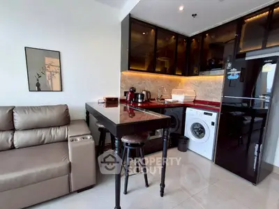 Modern kitchen with sleek appliances and cozy seating area in stylish apartment.