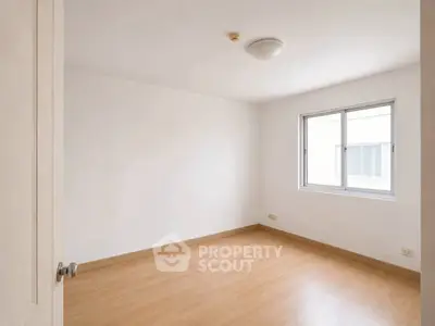 Spacious empty room with wooden flooring and large window, perfect for customization.