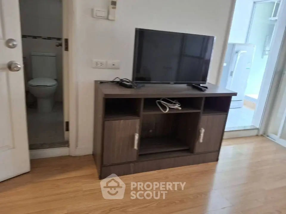 Compact living room with TV stand and adjacent bathroom in modern apartment