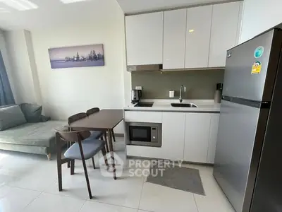 Modern kitchen with sleek cabinetry, dining set, and stainless steel appliances in a cozy apartment.