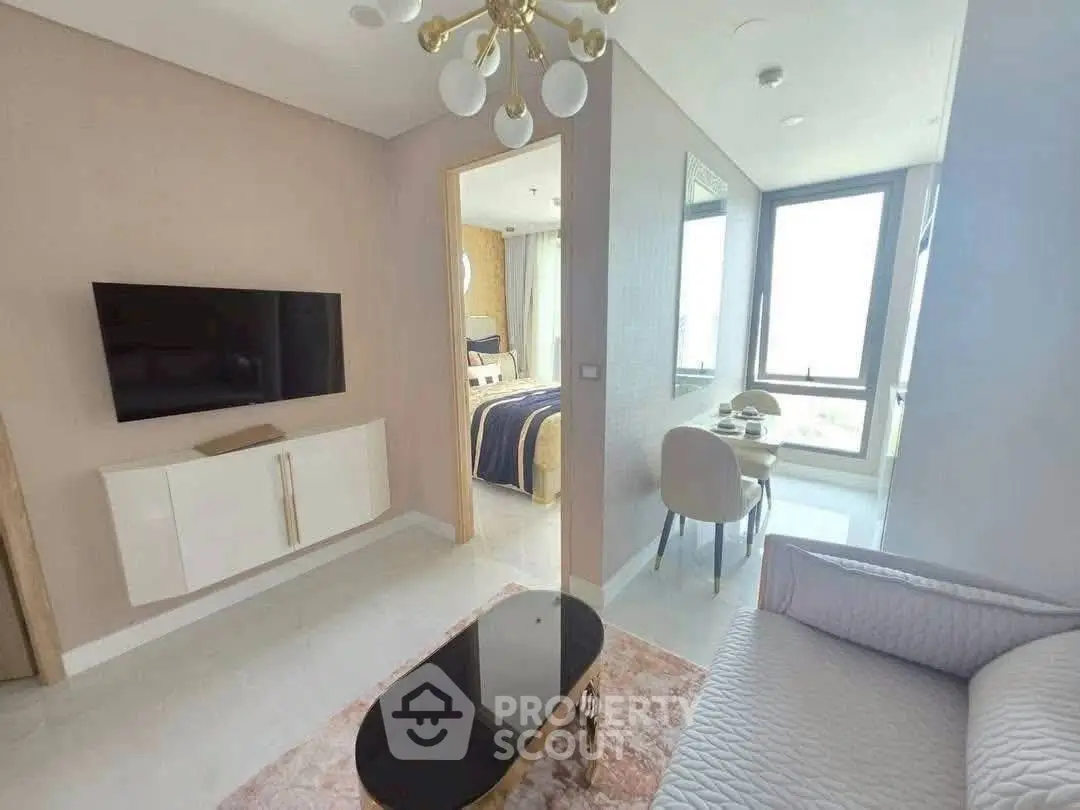 Modern living room with elegant decor, flat-screen TV, and cozy seating area, leading to a stylish dining space.