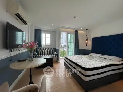 Chic bedroom with modern decor, featuring a plush bed, stylish seating, and a balcony with city views.
