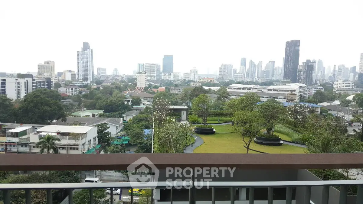 Stunning cityscape view from a high-rise balcony overlooking lush greenery and urban skyline.