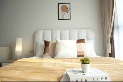 Modern bedroom with stylish decor and natural light, featuring a cozy bed and elegant lighting.