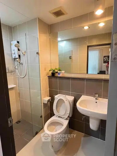 Modern bathroom with glass shower and sleek fixtures in contemporary apartment.