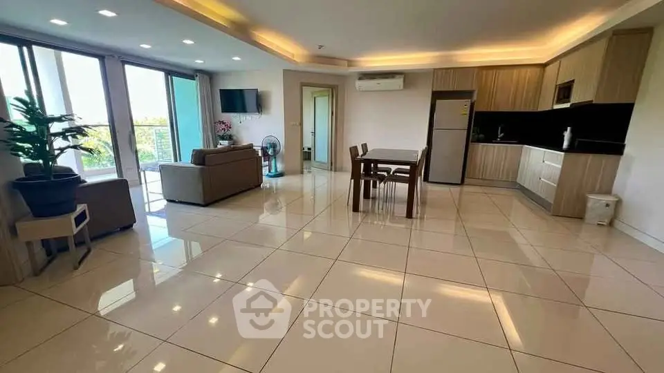 Spacious open-plan living room with modern kitchen and large windows.