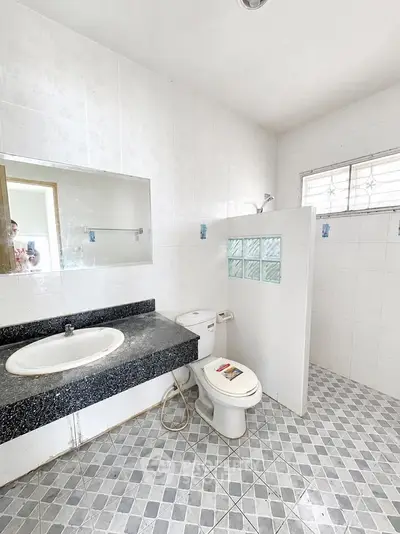 Spacious bathroom with modern fixtures and tiled flooring, featuring a large mirror and natural light.