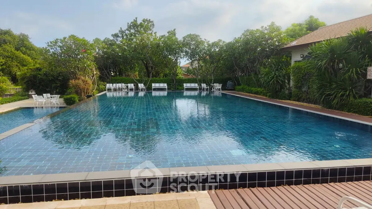 Luxurious outdoor pool surrounded by lush greenery and elegant seating, perfect for relaxation.