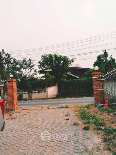 Charming suburban entrance with brick pillars and wrought iron gate, perfect for a welcoming home.
