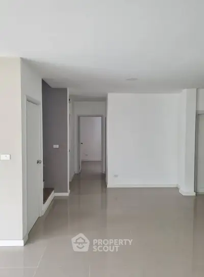 Spacious empty room with sleek tile flooring and neutral walls, perfect for customization.