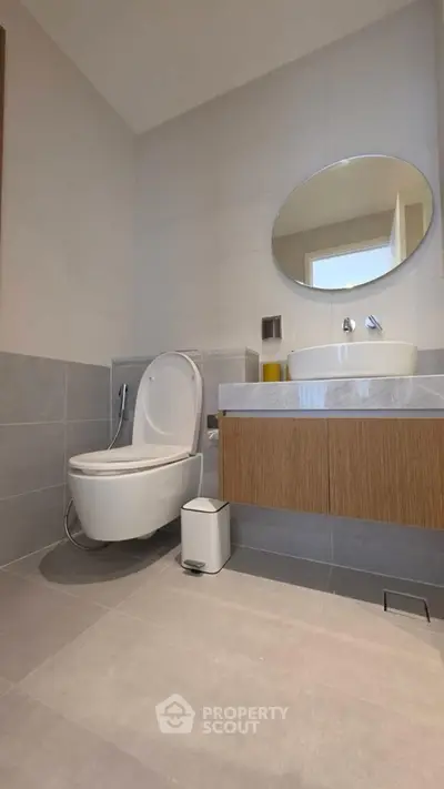 Modern bathroom with sleek fixtures and minimalist design, featuring a round mirror and elegant vanity.