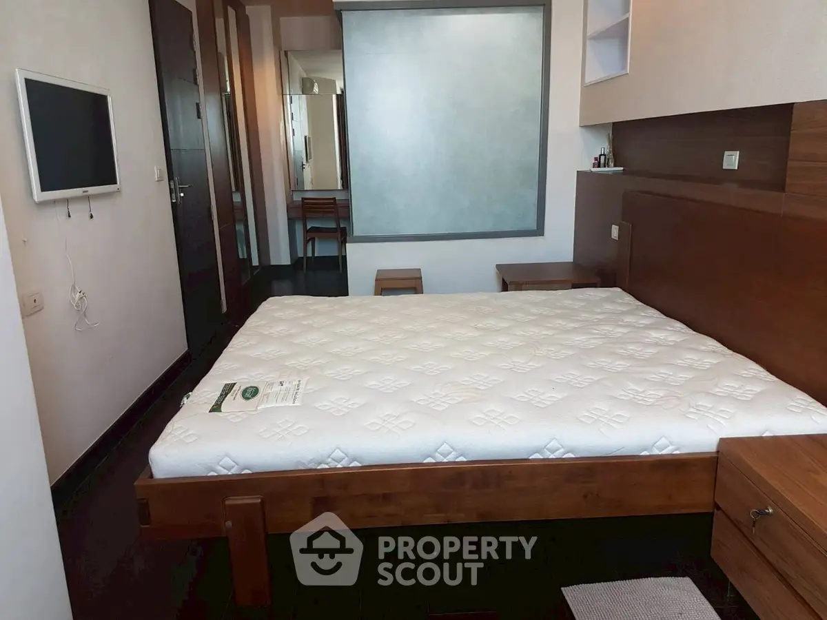 Modern bedroom with wooden furniture and wall-mounted TV, showcasing a minimalist design.