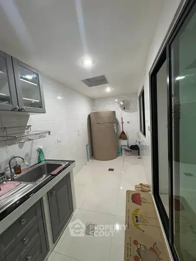 Modern kitchen with sleek cabinetry and stainless steel sink, featuring a compact layout and bright lighting.