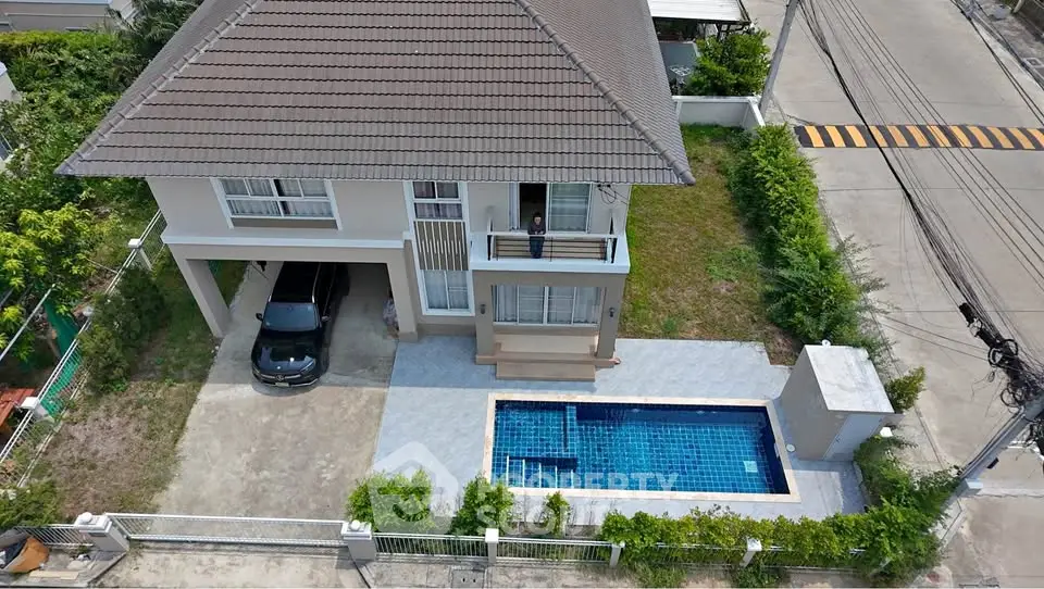 Stunning aerial view of a modern two-story house with private pool and carport in a serene neighborhood.