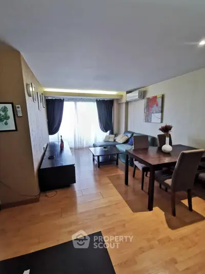 Spacious living room with modern decor and natural light, featuring a cozy seating area and dining table.
