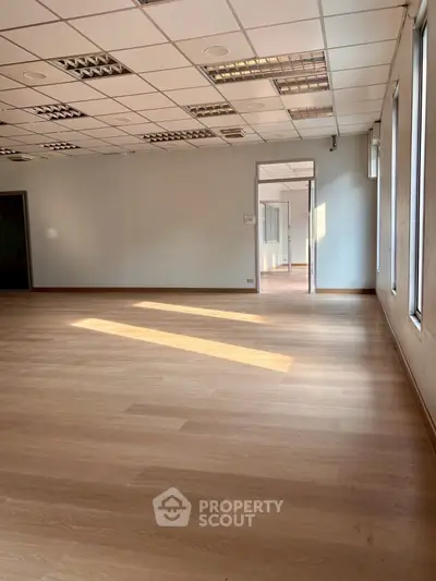 Spacious office space with large windows and wooden flooring, ideal for business setup.