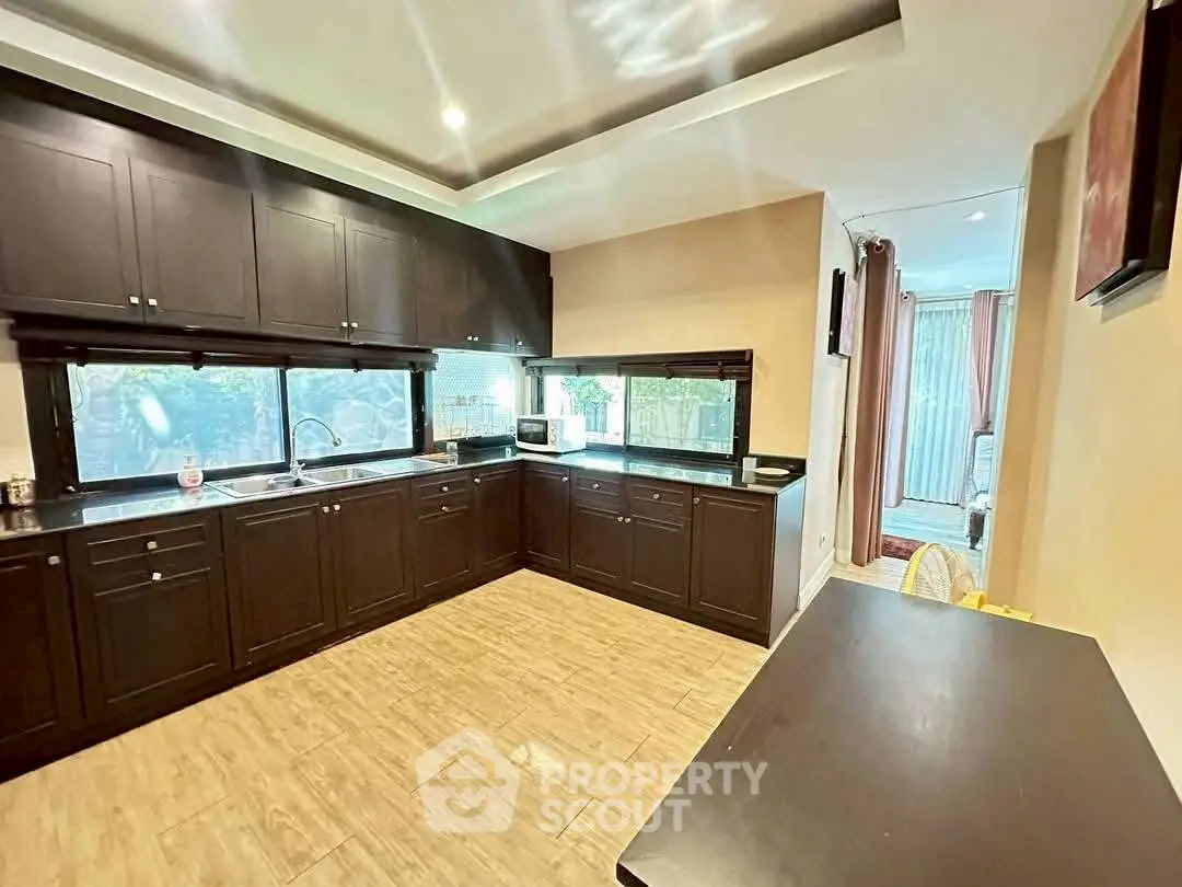 Spacious kitchen with dark cabinetry and open layout, featuring modern appliances and ample natural light.