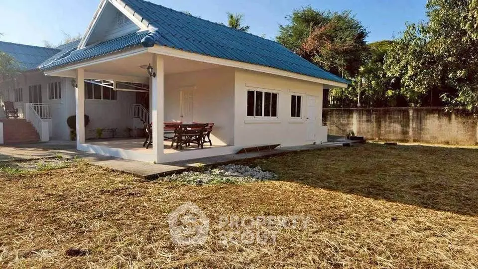 Charming single-story home with blue roof and spacious yard, perfect for outdoor activities and relaxation.