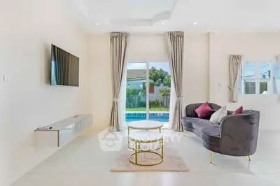 Modern living room with elegant decor and pool view, featuring a sleek TV and stylish furniture.