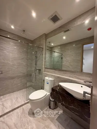 Luxurious modern bathroom with marble tiles and glass shower enclosure