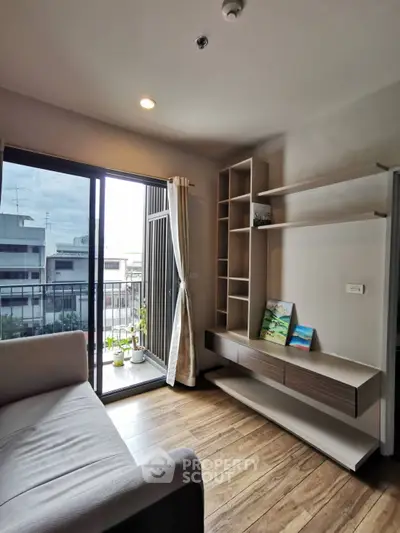 Modern living room with balcony view, sleek shelving, and cozy ambiance in urban apartment.