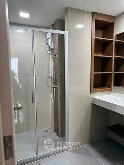 Modern bathroom with glass shower and built-in shelving, perfect for contemporary living.