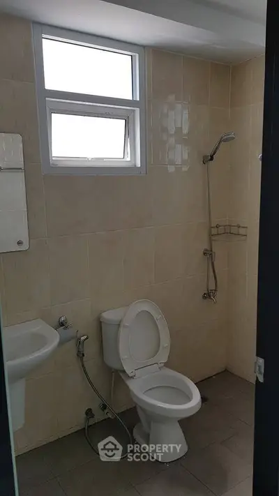 Compact bathroom with shower and toilet in a tiled setting