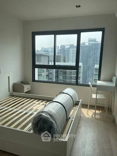 Bright bedroom with large window offering stunning city view, featuring a minimalist design and wooden flooring.