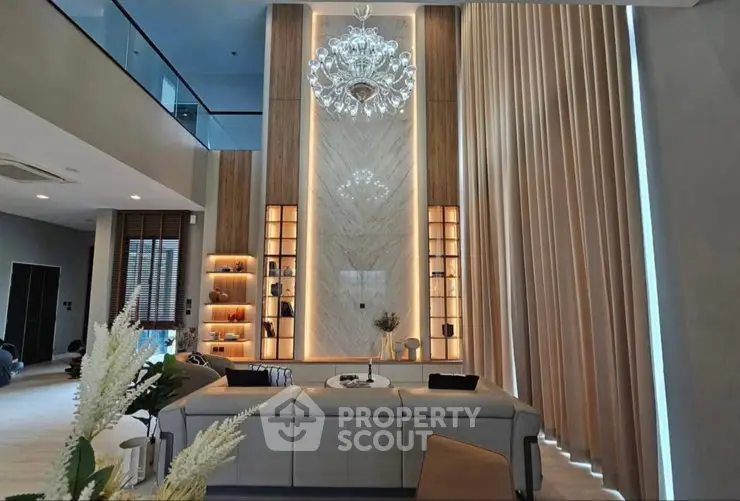 Luxurious living room with high ceilings, elegant chandelier, and modern decor