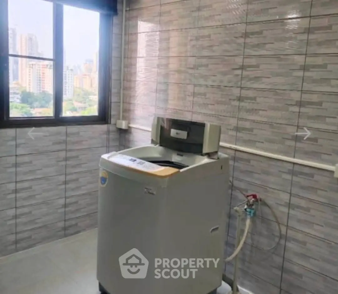 Spacious laundry room with modern washing machine and city view window.