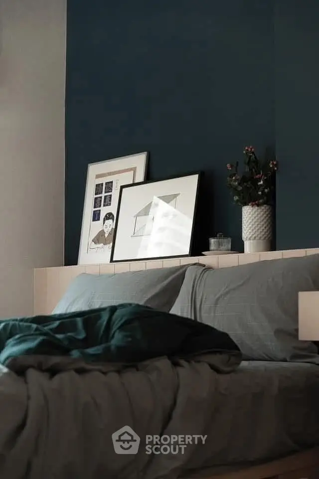 Cozy bedroom with stylish decor and framed art on a dark accent wall.