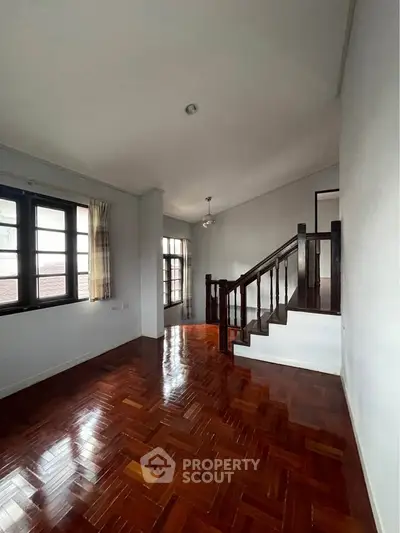 Spacious living room with wooden flooring and staircase in elegant home
