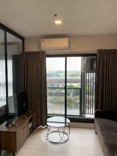 Modern living room with large window and stylish furniture, offering a cozy and bright atmosphere.
