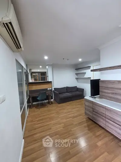 Modern living room with wooden flooring, cozy sofa, and sleek TV unit.