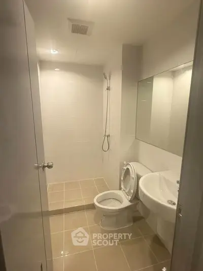 Modern bathroom with sleek fixtures and neutral tiles, featuring a shower and toilet.