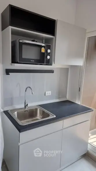 Modern compact kitchen with microwave and sleek cabinetry
