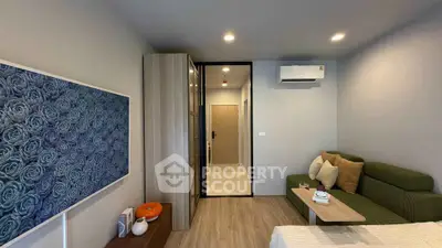 Modern bedroom with green sofa, wall art, and air conditioning in stylish apartment.