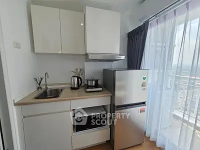 Modern compact kitchen with appliances and balcony view in high-rise apartment