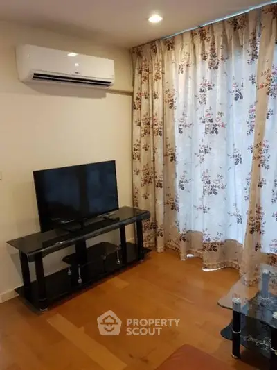 Cozy living room with air conditioning and floral curtains, perfect for relaxation.