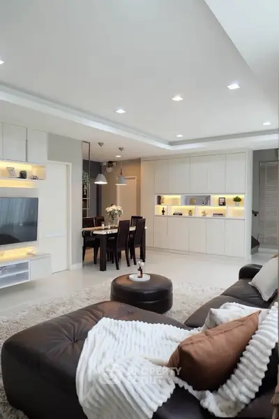 Luxurious modern living room with elegant dining area, featuring sleek built-in cabinets and cozy seating.