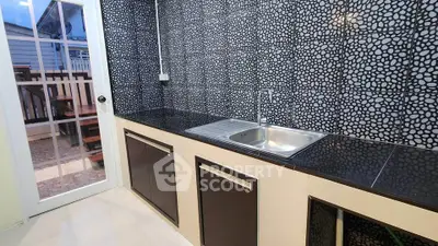 Modern kitchen with sleek black countertops and unique patterned backsplash