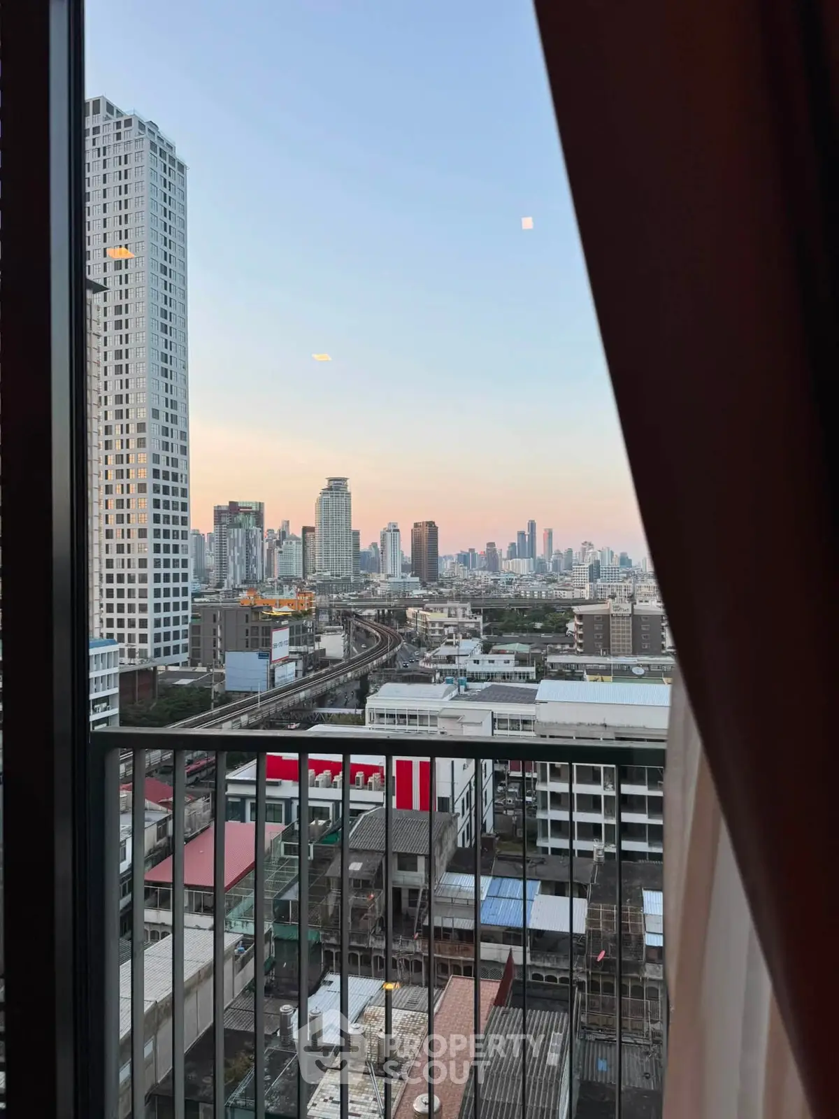 Stunning cityscape view from a high-rise balcony at sunset, showcasing urban skyline and vibrant city life.