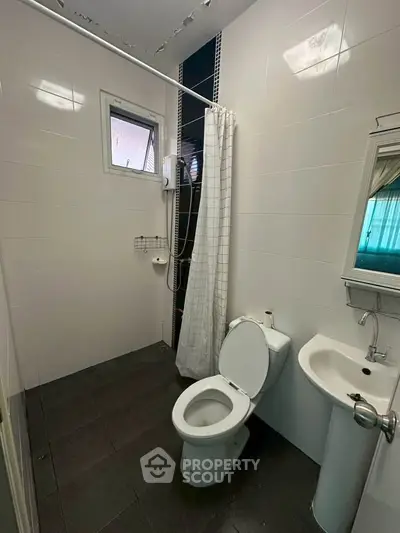 Compact bathroom with shower, toilet, and sink in modern apartment.