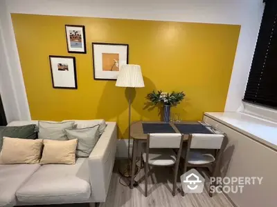 Cozy and inviting living space with a vibrant yellow accent wall, comfortable seating, and a chic dining area perfect for intimate gatherings.